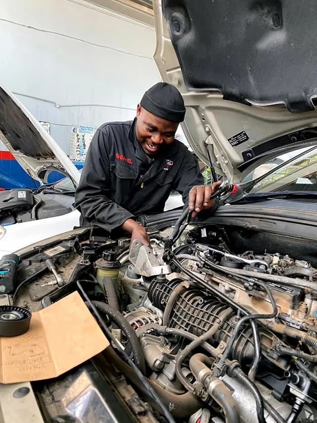 A mechanic smiling as he works on a car engine