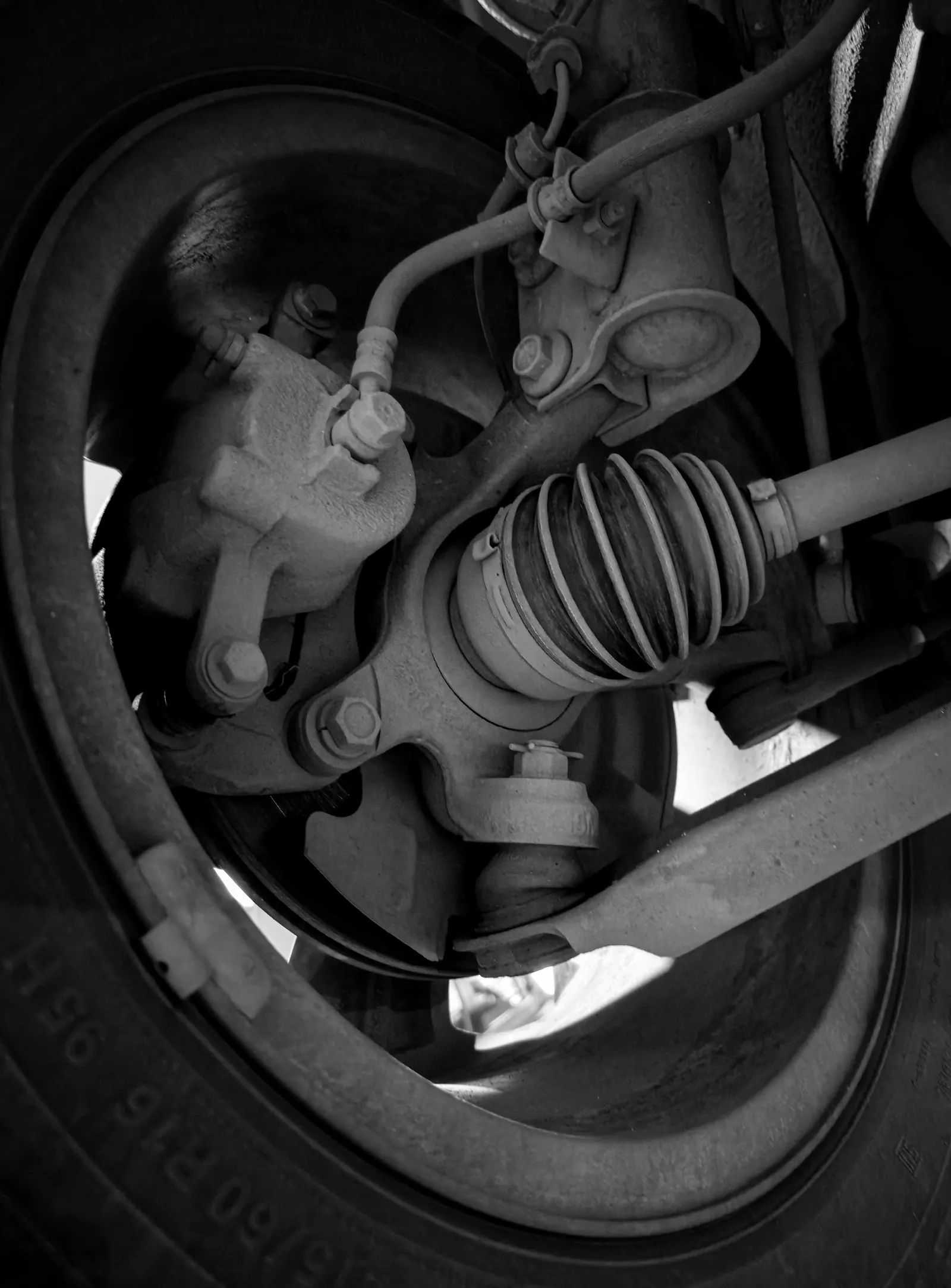 Front suspension and drive shaft behind a car wheel